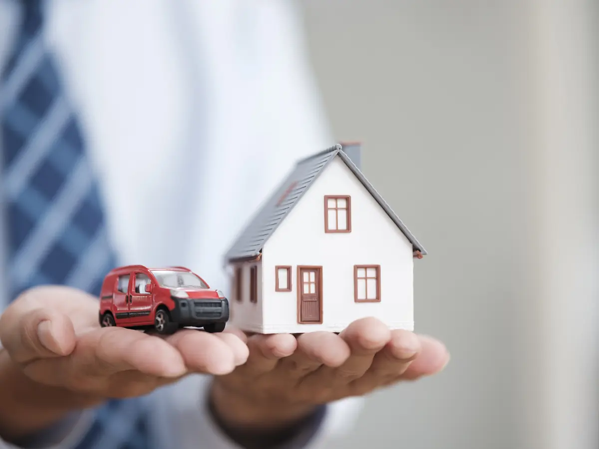 Hand hält Modellhaus und Modellauto